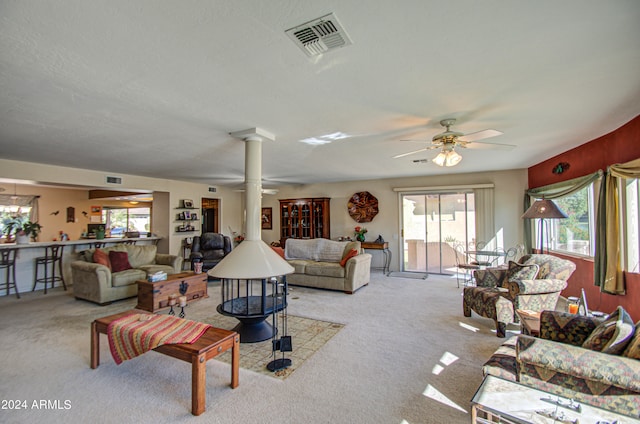 carpeted living room featuring a wealth of natural light, ceiling fan, and decorative columns