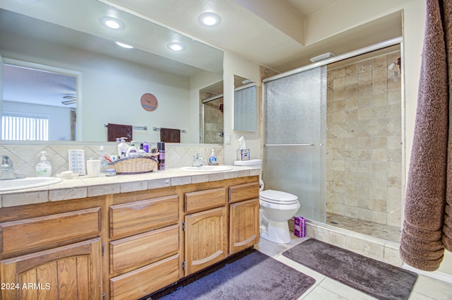 bathroom featuring a shower with door, tasteful backsplash, vanity, tile patterned floors, and toilet