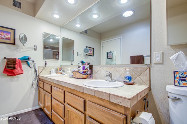 bathroom with vanity, toilet, and tasteful backsplash