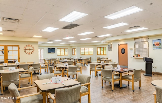 dining area with light hardwood / wood-style floors and a paneled ceiling