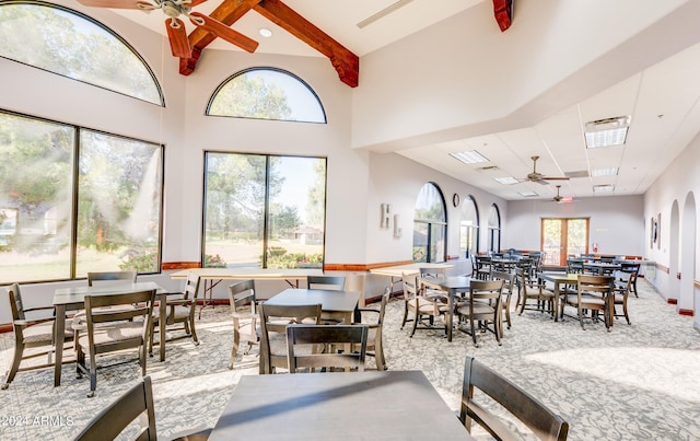 dining area featuring beam ceiling, ceiling fan, and a towering ceiling