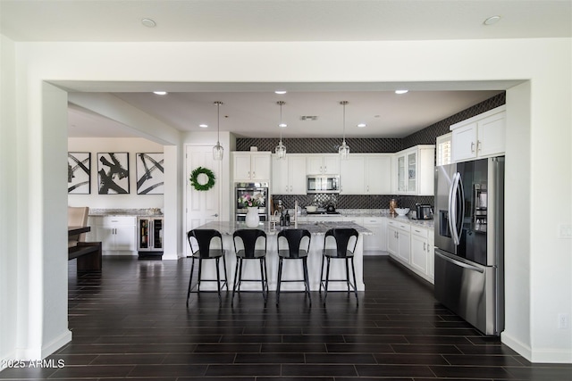 kitchen featuring dark wood-style flooring, a kitchen breakfast bar, stainless steel appliances, and white cabinetry