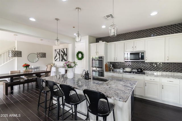 kitchen featuring stainless steel appliances, visible vents, white cabinetry, and dark wood-style flooring