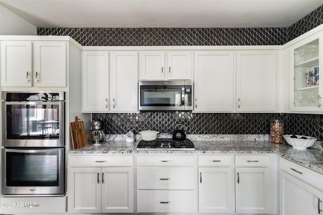 kitchen with white cabinets, glass insert cabinets, and appliances with stainless steel finishes