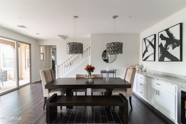 dining space featuring baseboards, visible vents, stairs, and dark wood finished floors