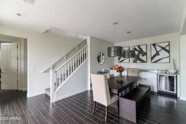 dining room with dark wood-type flooring, baseboards, beverage cooler, and stairs