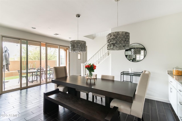 dining room with visible vents, baseboards, wood tiled floor, and stairs