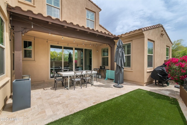 rear view of house featuring a patio area, outdoor dining area, and stucco siding