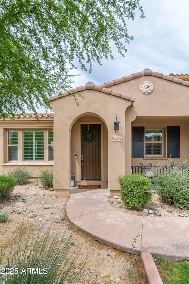 entrance to property featuring a tiled roof and stucco siding