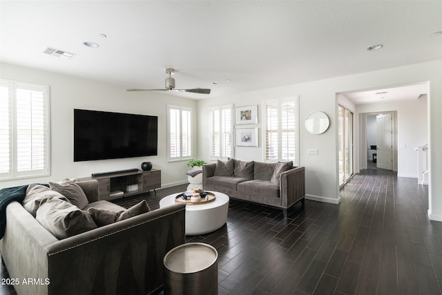 living room with visible vents, baseboards, dark wood-type flooring, and ceiling fan