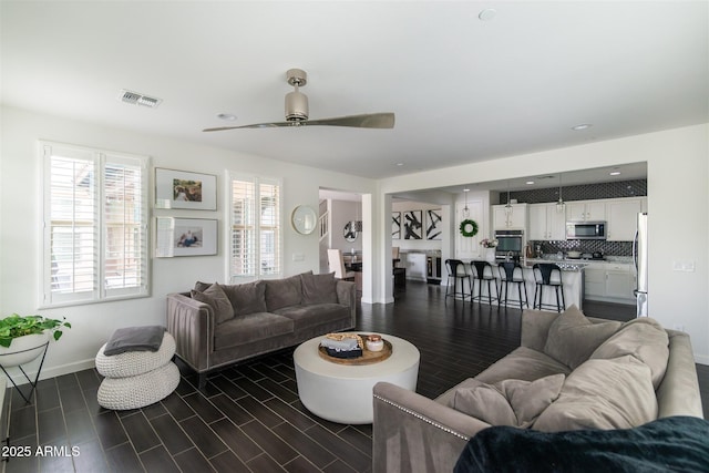 living room featuring recessed lighting, wood tiled floor, visible vents, a ceiling fan, and baseboards