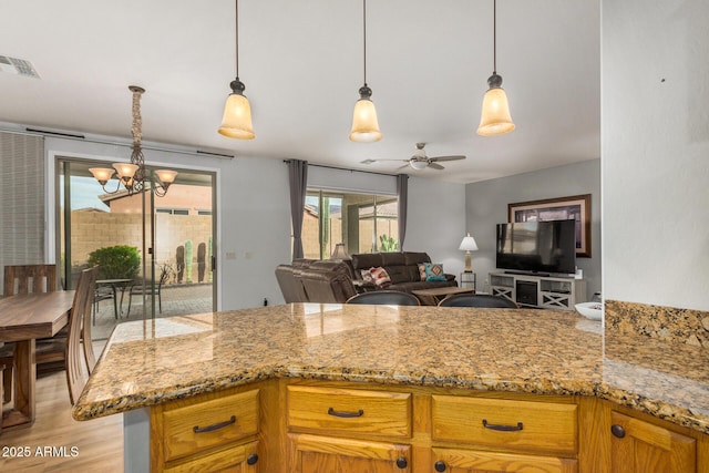 kitchen with light stone countertops, decorative light fixtures, and ceiling fan with notable chandelier