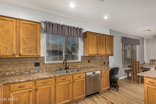 kitchen with stone counters, sink, stainless steel dishwasher, backsplash, and light wood-type flooring