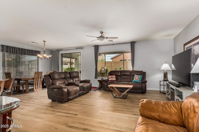 living room with light hardwood / wood-style floors and ceiling fan with notable chandelier