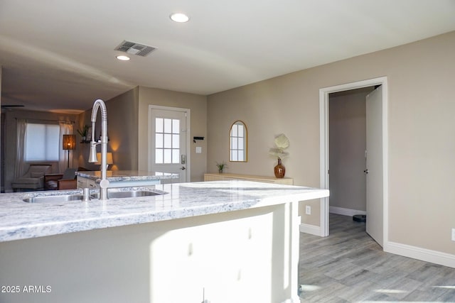 kitchen with light stone countertops, light hardwood / wood-style flooring, and sink