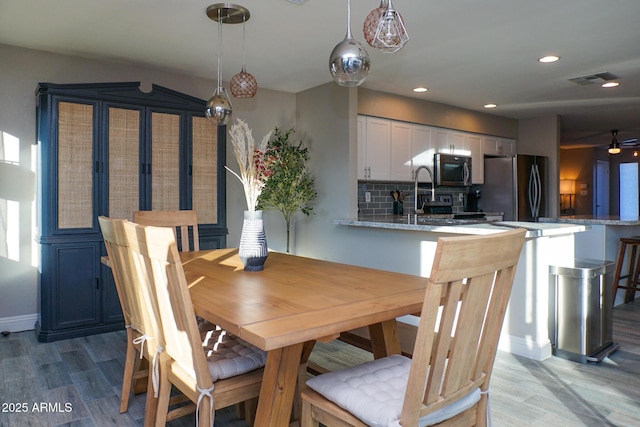 dining area featuring sink, light wood-type flooring, and ceiling fan