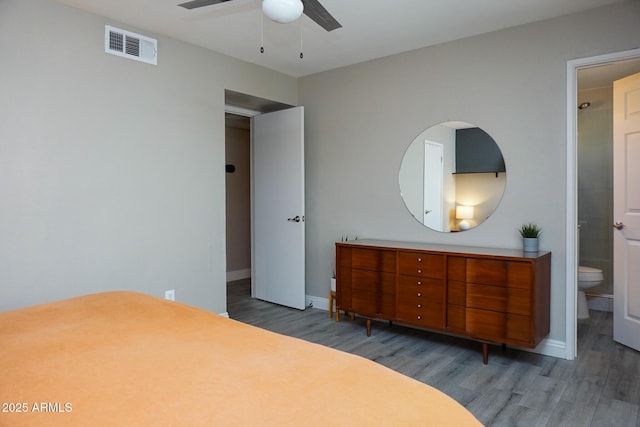 bedroom with ceiling fan, dark wood-type flooring, and ensuite bath