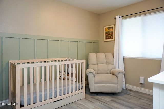 bedroom featuring a nursery area and light hardwood / wood-style flooring