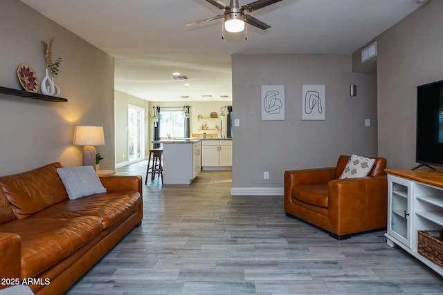 living room featuring ceiling fan and light hardwood / wood-style floors