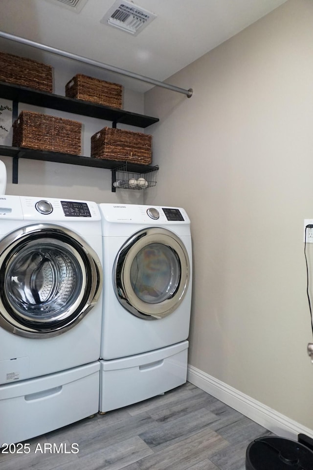 laundry area featuring washing machine and clothes dryer and light hardwood / wood-style flooring