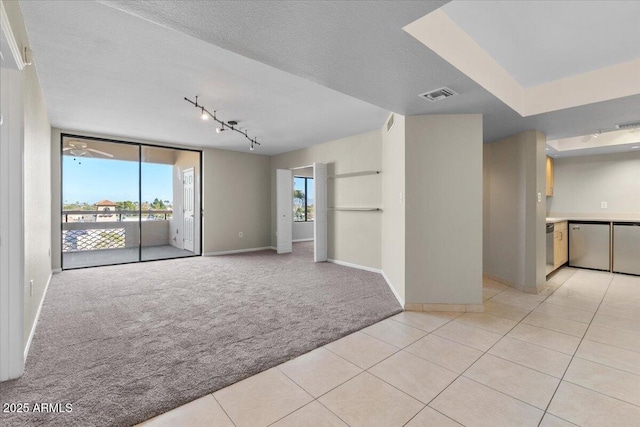 carpeted empty room featuring track lighting, floor to ceiling windows, and a textured ceiling