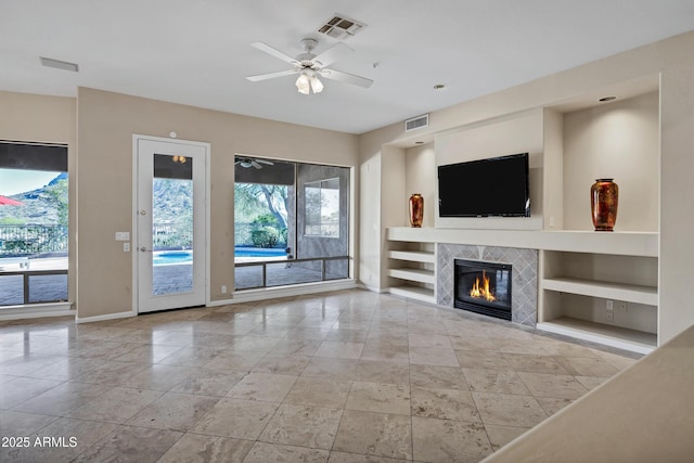 13945 E Gail Rd, Scottsdale, AZ 85259 - unfurnished living room featuring built in features, a ceiling fan, and a tiled fireplace