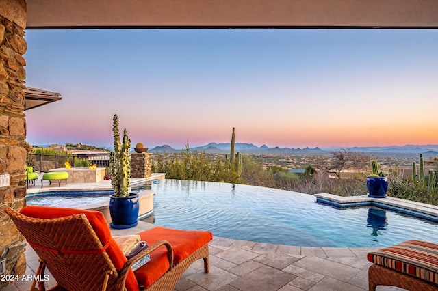 11070 E Rolling Rock Dr, Scottsdale, AZ 85262 - pool at dusk with an infinity pool, a patio area, and a mountain view