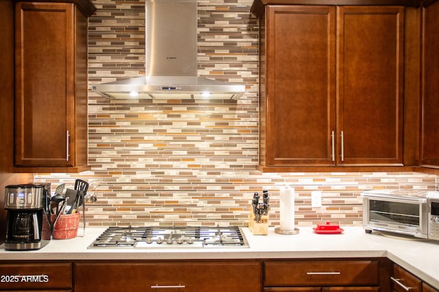 kitchen with exhaust hood, stainless steel gas stovetop, and decorative backsplash