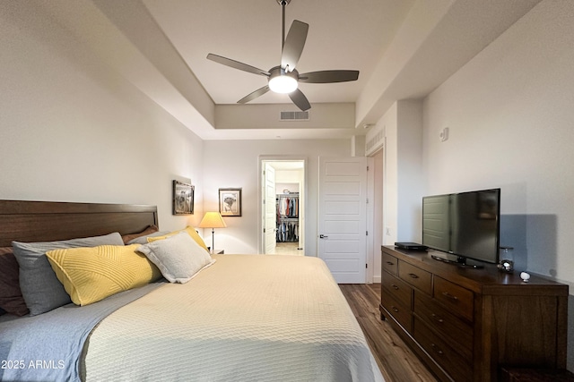 bedroom with ceiling fan, dark wood-type flooring, a spacious closet, and a closet