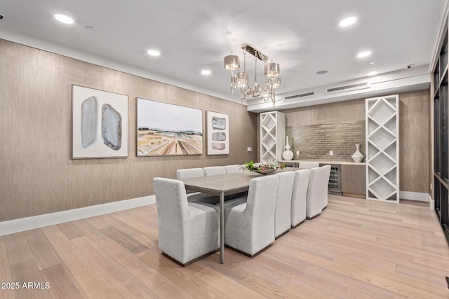 dining space featuring a notable chandelier, light hardwood / wood-style flooring, and wine cooler