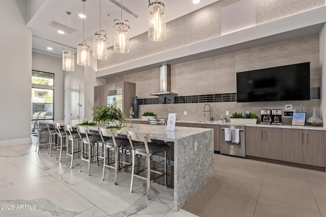 kitchen featuring wall chimney exhaust hood, hanging light fixtures, stainless steel appliances, a spacious island, and a breakfast bar