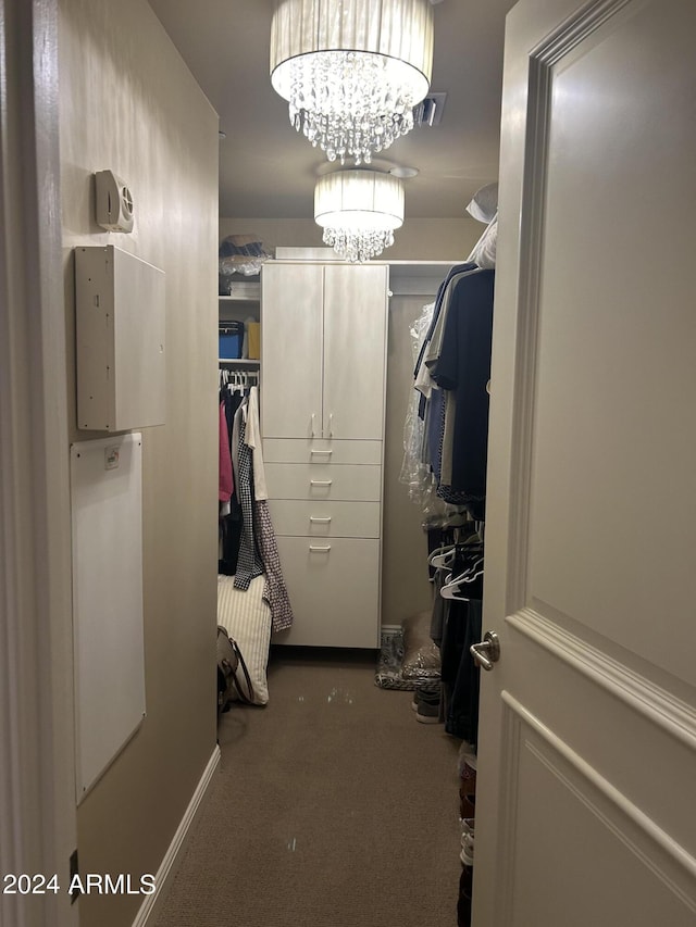 walk in closet featuring carpet flooring and a notable chandelier