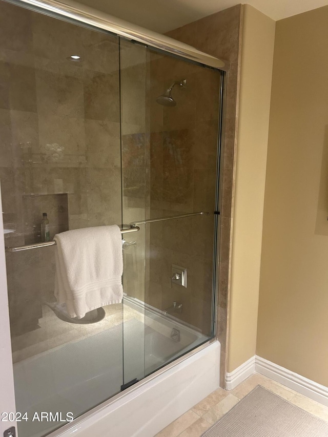 bathroom with tile patterned floors and shower / bath combination with glass door