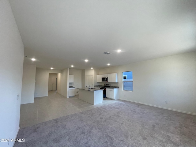 kitchen with white cabinets, appliances with stainless steel finishes, a center island, and light carpet