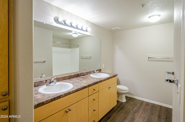 bathroom featuring toilet, vanity, wood-type flooring, and a textured ceiling