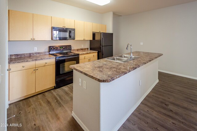 kitchen featuring dark wood-type flooring, sink, black appliances, and an island with sink