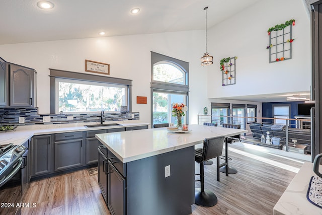 kitchen featuring tasteful backsplash, sink, electric range, light hardwood / wood-style flooring, and hanging light fixtures