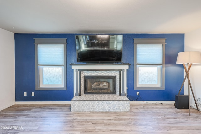 unfurnished living room with wood-type flooring, a fireplace, and a wealth of natural light