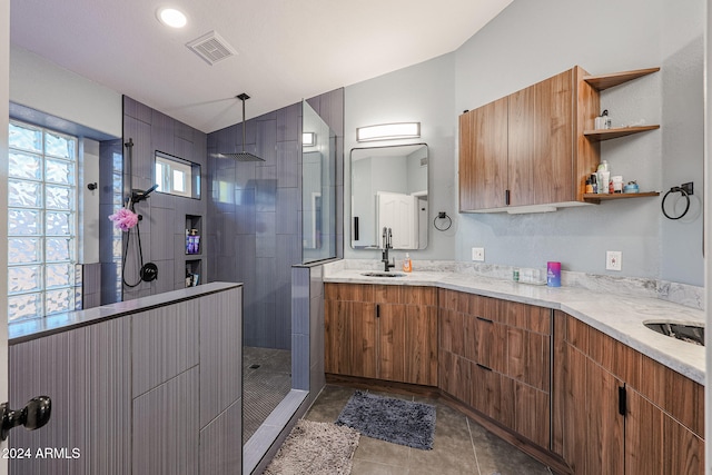 bathroom with tile patterned floors, vanity, lofted ceiling, and tiled shower