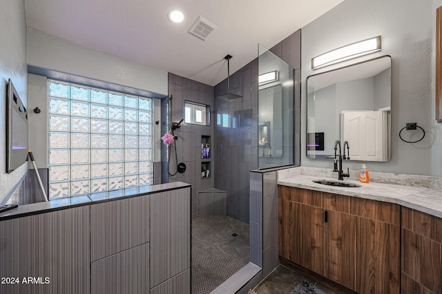 bathroom with vanity, lofted ceiling, and tiled shower