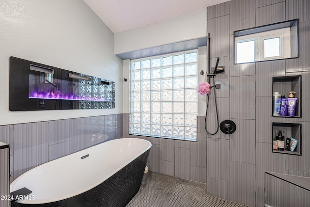 bathroom with tile patterned flooring, a textured ceiling, a wealth of natural light, and independent shower and bath