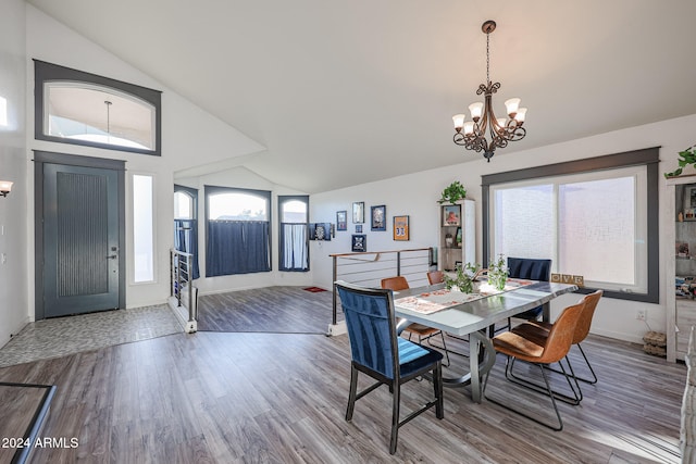 dining space with hardwood / wood-style floors, vaulted ceiling, and a notable chandelier