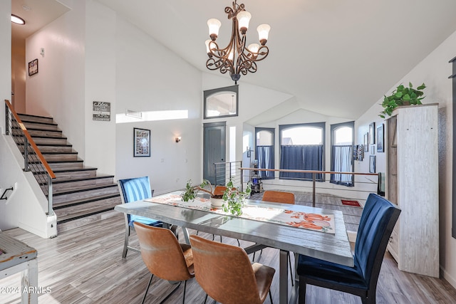 dining space featuring light hardwood / wood-style flooring, high vaulted ceiling, and a chandelier