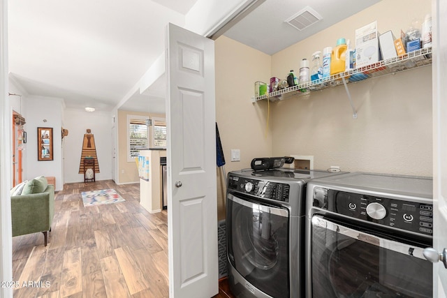 clothes washing area with hardwood / wood-style floors and washer and clothes dryer