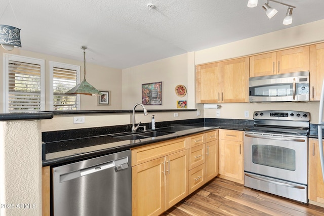 kitchen featuring sink, light hardwood / wood-style flooring, light brown cabinets, appliances with stainless steel finishes, and pendant lighting