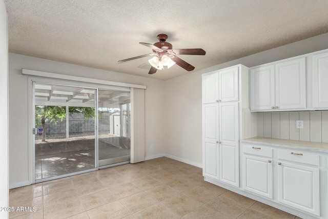spare room with baseboards, a textured ceiling, ceiling fan, and light tile patterned floors