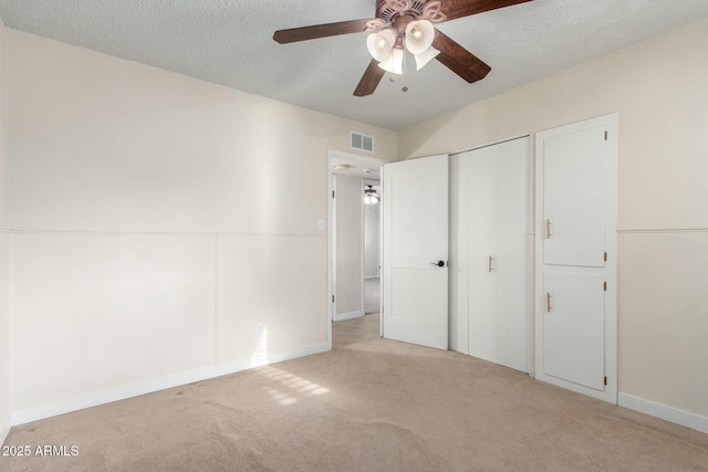 unfurnished bedroom featuring carpet flooring, a textured ceiling, ceiling fan, visible vents, and a closet