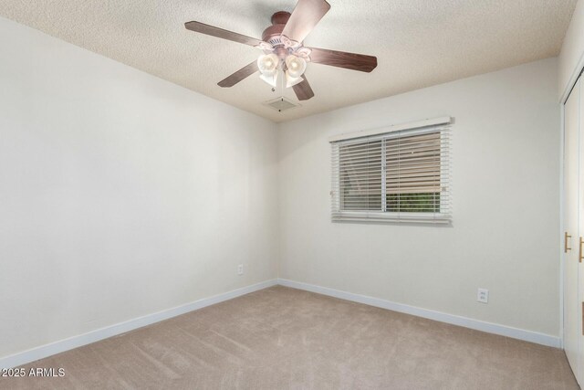 empty room with baseboards, a textured ceiling, visible vents, light carpet, and ceiling fan