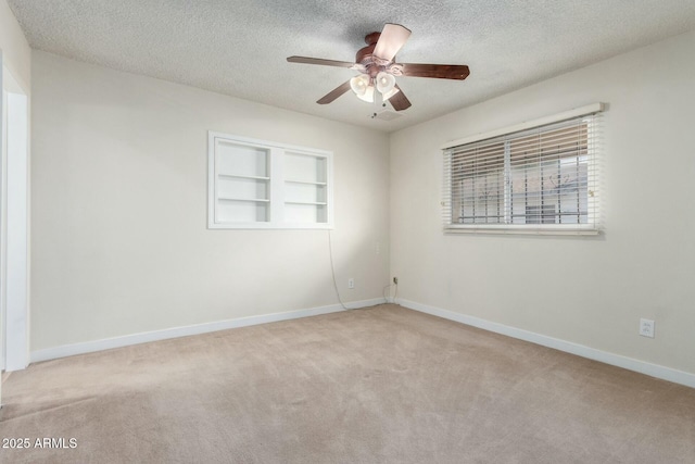 carpeted spare room with built in shelves, baseboards, ceiling fan, and a textured ceiling