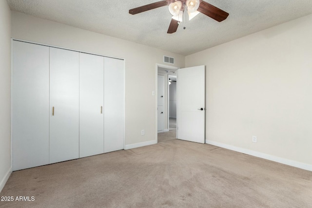 unfurnished bedroom with carpet flooring, a textured ceiling, a closet, and visible vents